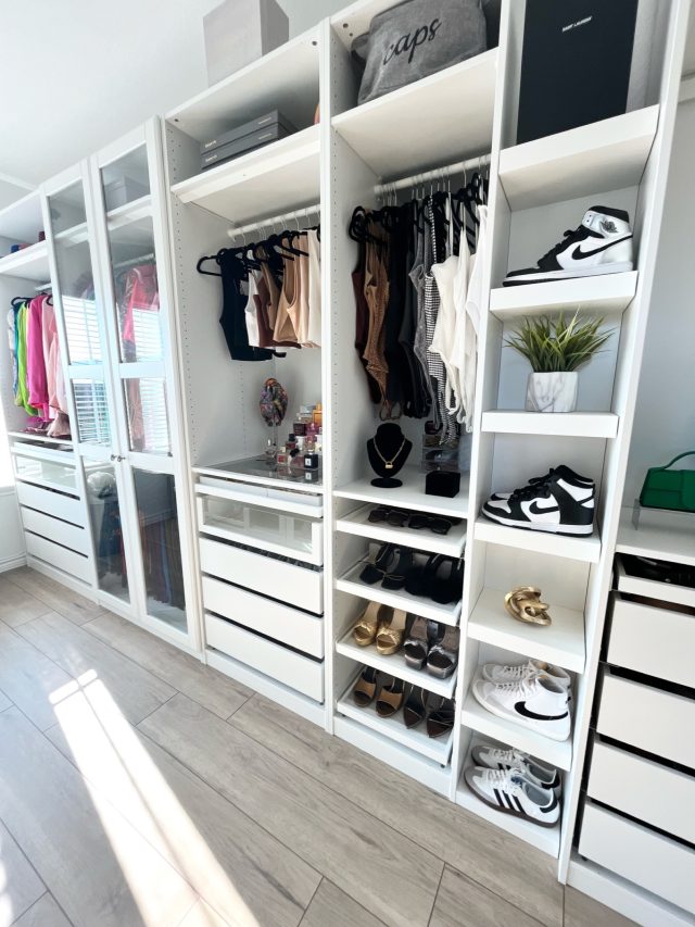 A walk-in closet with white built-ins, shelved shoes and a bank of drawers
