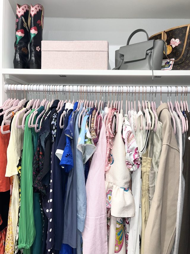 Handbags and a hat box shelved above a long rod of colorful dresses