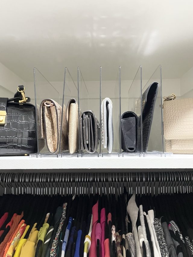Clutches and small bags standing upright between shelf dividers above two hanging rods