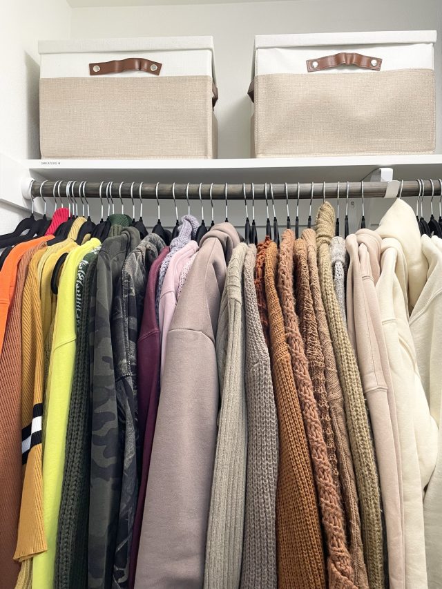 Labeled fabric bins above a double-hung rod of coats and folded sweaters
