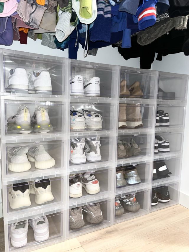 Clear shoe boxes filling a closet wall beneath a row of hanging children's coats