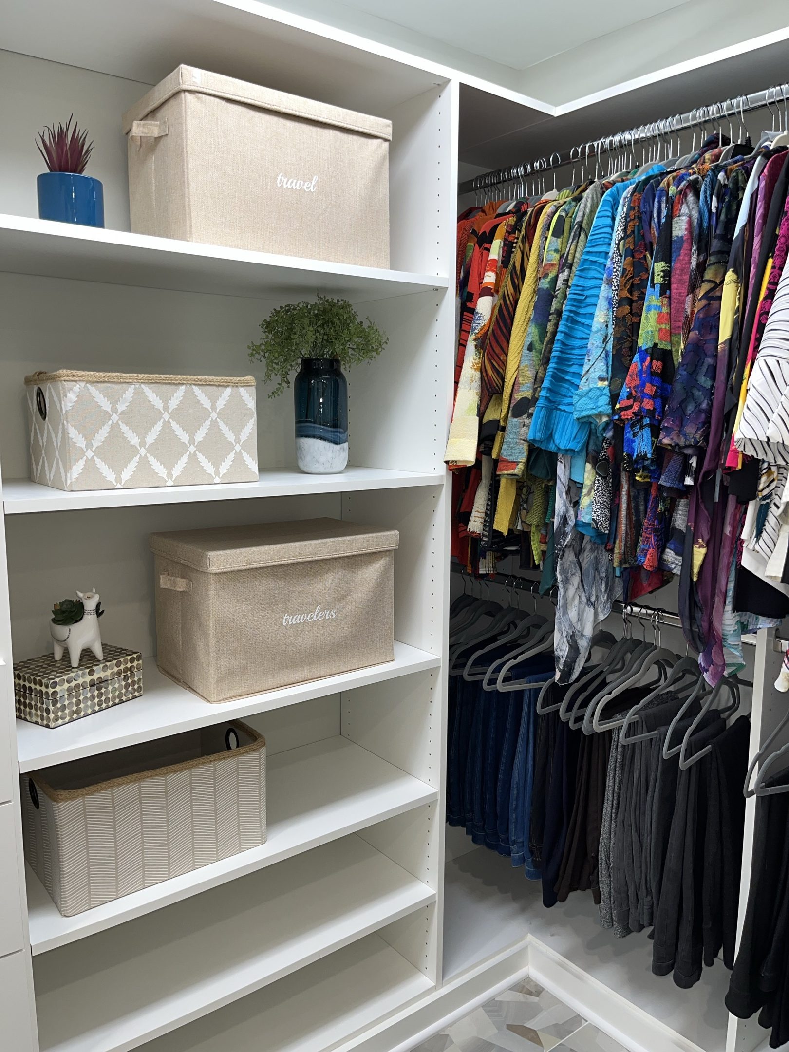 A walk-in closet with labeled fabric bins on open shelving and clothes hung by category on matching hangers