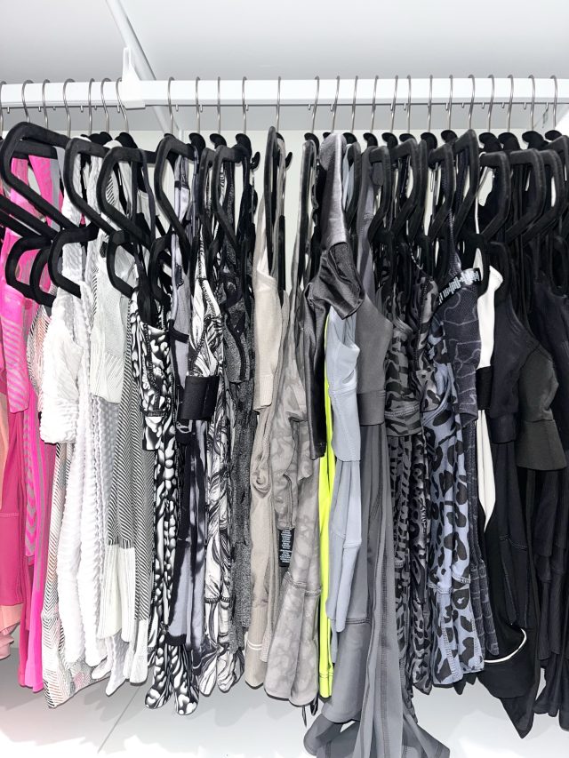 Evening dresses and gowns hung on black velvet hangers along one rod
