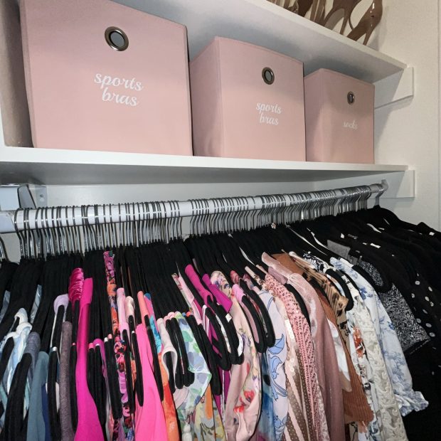 Pink storage boxes and heels above a row of hanging dresses and blouses