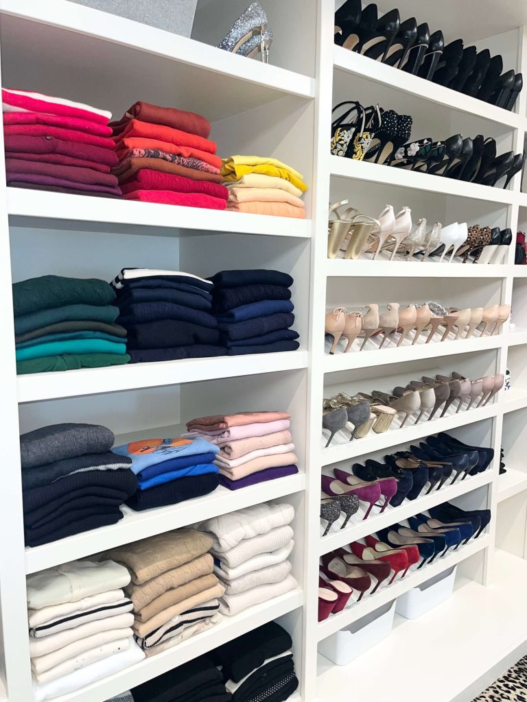 Folded clothing organized in stacks on open walk-in closet shelving