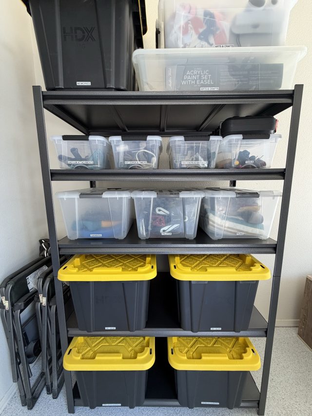 A steel garage rack holding clear bins above labeled black-and-yellow totes