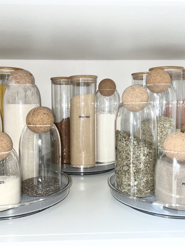 Glass canisters of flour, sugar and spices on turntables in a pantry cabinet