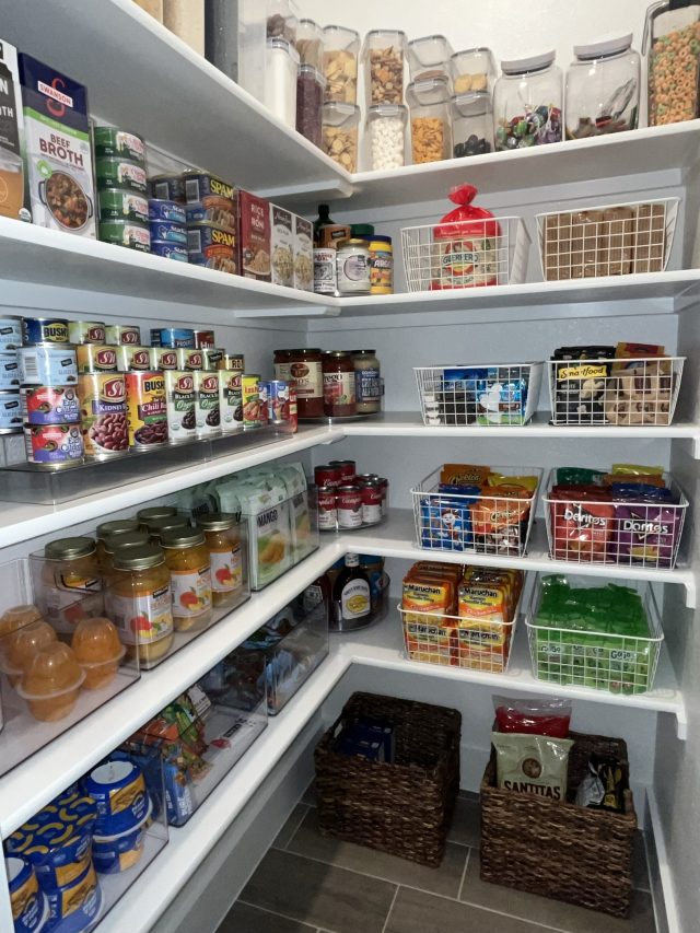 A corner pantry with canned goods, clear bins and woven baskets on every shelf