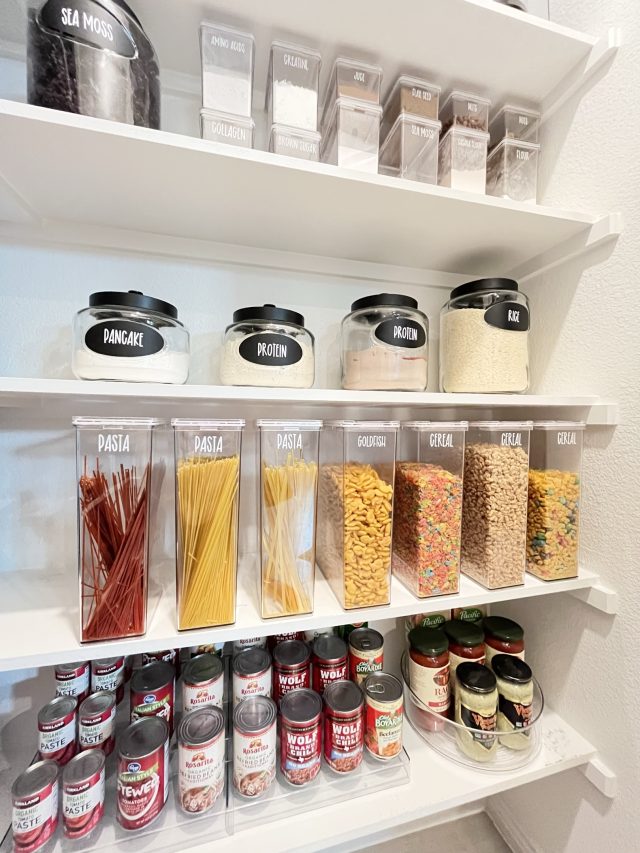 Pasta, cereal and spices in labeled canisters above rows of canned tomatoes