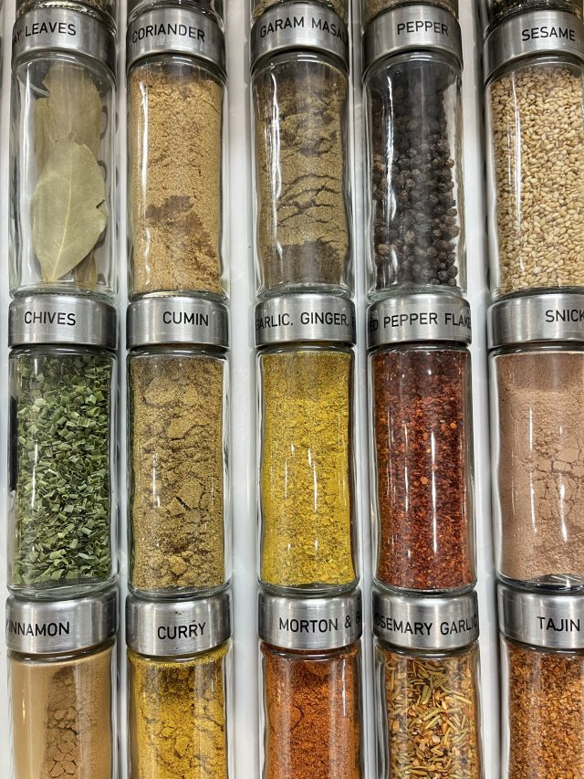 Tall glass spice jars labeled on the cap and stored on their sides