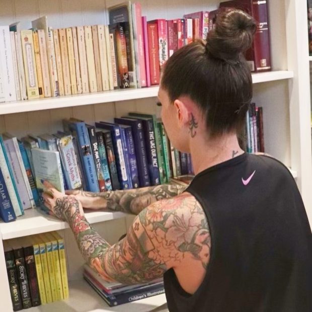 Ashley Matteson shelving books by size and color on a client's built-in